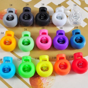 Può includere: Quindici chiusure a scatto in plastica di vari colori, tra cui grigio, nero, bianco, trasparente, giallo, verde, rosa, viola, blu, azzurro, verde, giallo, arancione e rosso. Ogni chiusura ha un meccanismo a molla e un piccolo foro per attaccare un cordino o una corda.