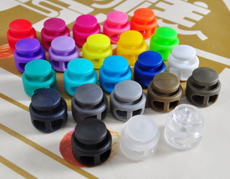 May include: Assortment of colorful plastic toggle clasps, also known as cord locks, in various colors including red, blue, green, yellow, purple, gray, and white.