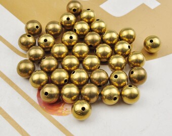 May include: A pile of gold-colored metal beads with a hole through the center of each bead.