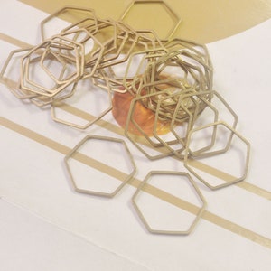 May include: A pile of gold-coloured metal hexagonal rings. The rings are stacked on top of each other and are arranged in a random pattern.