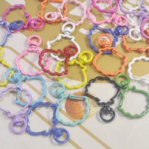 May include: Assortment of colorful metal keychains with a flower-shaped design. Each keychain has a swivel clasp and a spring-loaded hook.