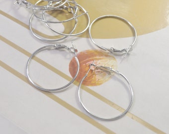 May include: A set of four silver hoop earrings. The earrings are all the same size and have a simple, classic design.