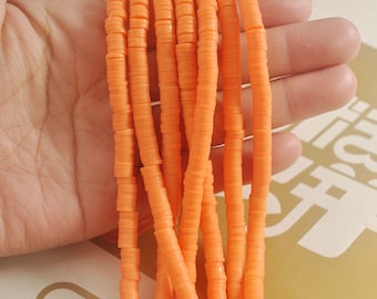 May include: A strand of orange polymer clay beads, each bead is a flat disc with a hole in the center. The beads are stacked on top of each other, creating a long, continuous strand.