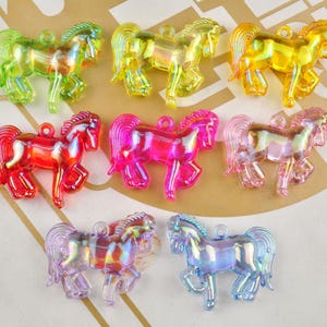 Puede incluir: Surtido de diez dijes de caballo de plástico iridiscente en varios colores, incluyendo rosa, azul, rojo, amarillo y verde. Los dijes miden aproximadamente 5 cm de largo y tienen un agujero en la parte superior para colgar.