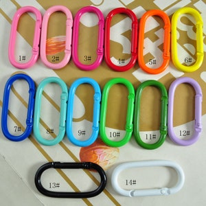 May include: Assortment of 14 colorful metal key rings in various sizes. The key rings are numbered 1 through 14. The key rings are oval shaped and have a spring-loaded clasp.