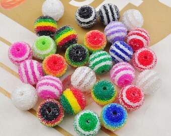 May include: Assortment of colourful striped and patterned beads. The beads are made of plastic and have a textured surface.