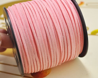 Könnte beinhalten: Eine Spule mit rosa Wildlederkordel, um eine schwarze Plastikspule gewickelt.