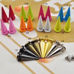 Op de afbeelding: Assortiment van kleurrijke metalen piramide studs in verschillende maten, met nummers 1 tot en met 12, en twee schroeven.
