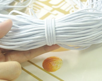 May include: A close-up of a bundle of white elastic cord. The cord is soft and flexible, and it is ideal for crafting projects.