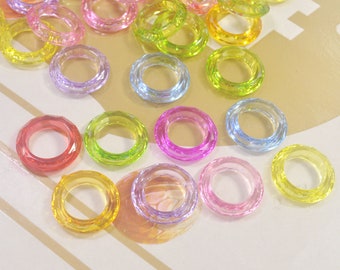 May include: Assortment of colorful plastic rings, some are translucent and some are opaque. The rings are in various shades of pink, red, green, yellow, and blue.