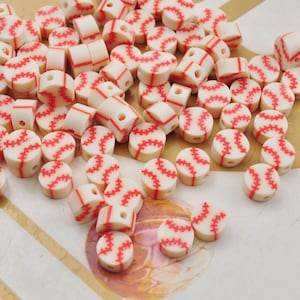May include: A large group of white and red baseball-themed beads. The beads are round and have a red stitching design.
