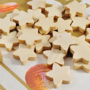 May include: A pile of unfinished wooden star-shaped beads. The beads are light brown and have a hole in the centre.