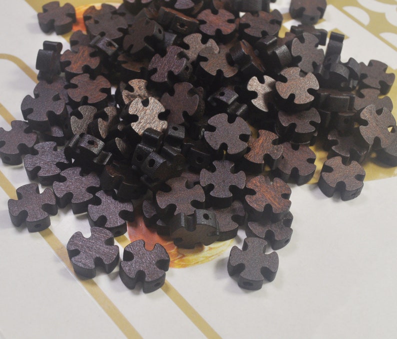 Puede incluir: Un mont&oacute;n de botones de madera marr&oacute;n oscuro con forma de estrella de cuatro puntas. Los botones tienen una superficie rugosa y texturizada.