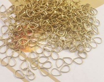 May include: A large pile of gold-colored metal teardrop-shaped pendant bails. The bails are about 1 inch long and have a small loop at the top.
