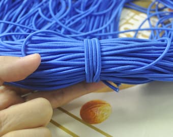 May include: A large spool of bright blue elastic cord. The cord is tightly wound and is being held in a hand.
