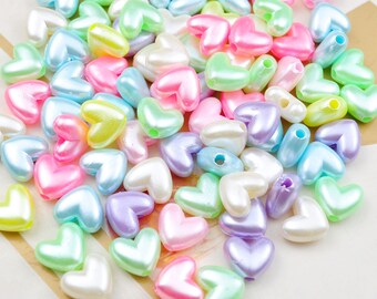 May include: A large assortment of pastel-colored plastic heart-shaped beads. The beads have a pearlescent finish and are perfect for crafting.