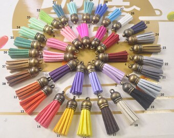 Puede incluir: Surtido de 38 borlas de gamuza de colores vivos con tapas de metal dorado. Las borlas están dispuestas en un círculo con los números del 1 al 38.