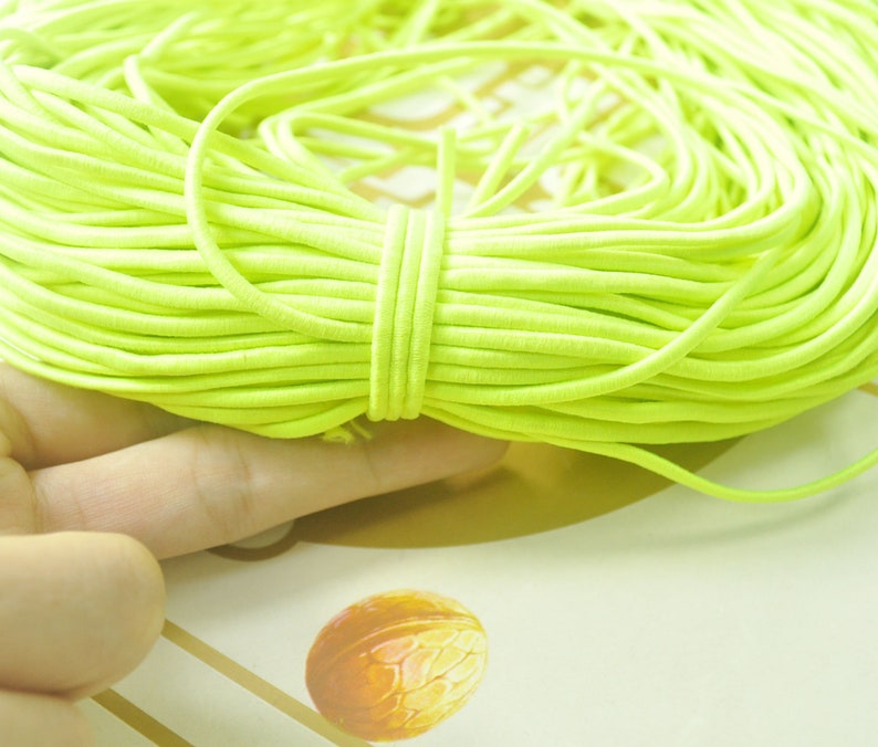 May include: A close-up of a large bundle of bright yellow elastic cord. The cord is tightly wound and appears to be made of a soft, flexible material.