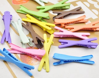 May include: A collection of colorful plastic hair clips in various shapes and sizes. The clips are in shades of pink, blue, purple, yellow, green, orange, and brown.