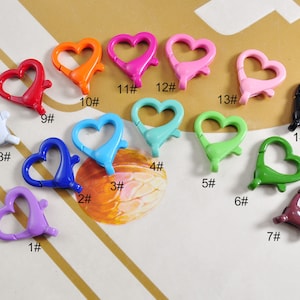 May include: Assortment of 14 heart-shaped metal clasps in various colors, including purple, blue, green, pink, red, orange, white, and black. Each clasp is numbered 1 through 14.