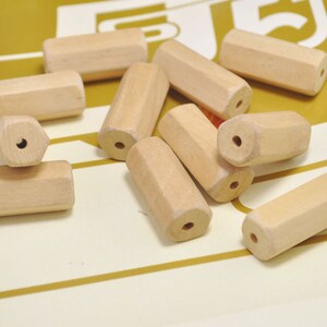 May include: A collection of ten natural wood beads, each with a hole drilled through the center. The beads are all different shapes and sizes, but they are all made of the same type of wood.