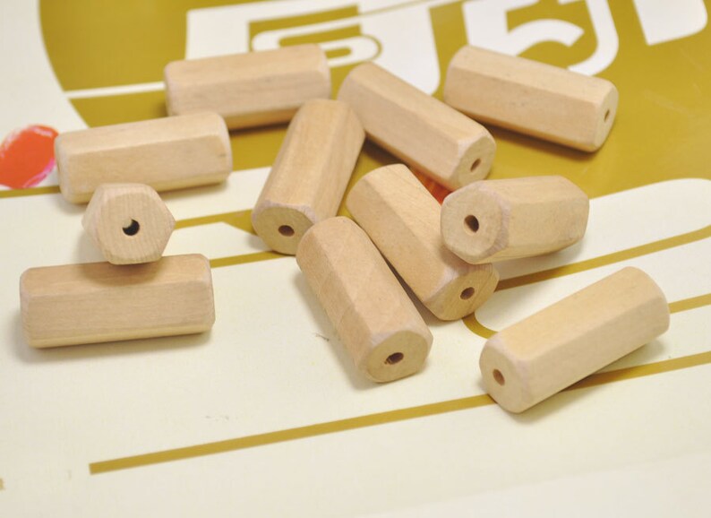 May include: A collection of ten natural wood beads, each with a hole drilled through the center. The beads are all different shapes and sizes, but they are all made of the same type of wood.