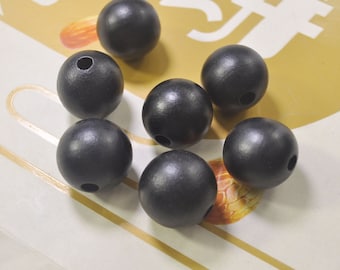May include: Seven black wooden beads with a hole in the center. The beads are round and smooth.