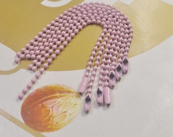 May include: A close-up of a pink beaded chain with metal ends. The chain is made of small, round beads and is about 12 inches long.