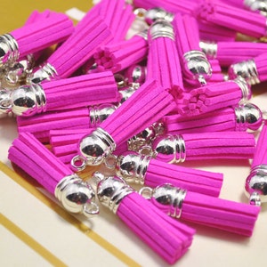 Peut inclure: Un tas de pompons rose vif avec des embouts et des boucles en métal argenté. Les pompons sont faits d'un matériau doux et duveteux et sont parfaits pour ajouter une touche de couleur et de texture à n'importe quel projet.