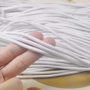 May include: A close-up of a large spool of white elastic cord. The cord is soft and flexible, and it is perfect for a variety of crafting projects.