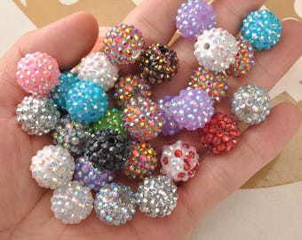 May include: A selection of colourful, sparkly beads in shades of pink, blue, silver, purple, red, and black. The round beads are covered in small, iridescent rhinestones. These beads are suitable for jewellery making and craft projects.
