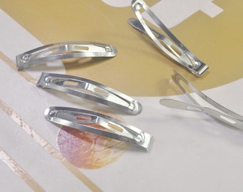 May include: Five silver metal hair clips. The clips are all the same size and shape, with a curved design and a small opening in the middle. They are commonly used to hold hair in place.