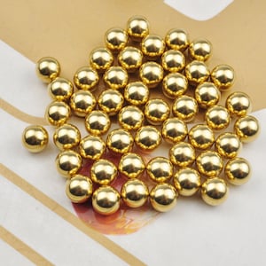 Pode incluir: Um monte de bolas de metal douradas brilhantes. As bolas são lisas e redondas, e todas são do mesmo tamanho.