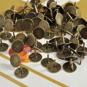 May include: A large quantity of antique gold-toned metal tacks with round heads and pointed tips.