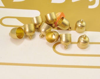 Puede incluir: Un grupo de diez tapas de metal de color dorado con un pequeño lazo en la parte superior. Las tapas son redondas y tienen un acabado liso y brillante.