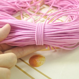 May include: A close-up of a large bundle of pink elastic string. The string is soft and pliable, and it is ideal for crafting or making jewellery.