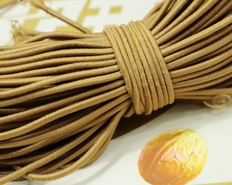 May include: A close-up of a spool of brown elastic cord. The cord is tightly wound and has a smooth, matte finish.