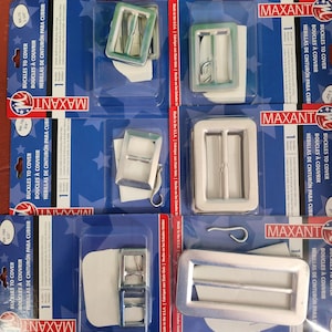 May include: Several packages of metal buckles for covering, in various shapes and sizes. The packages are blue and white, with the brand name "MAXANT" visible. The buckles are silver-colored and appear to be new.