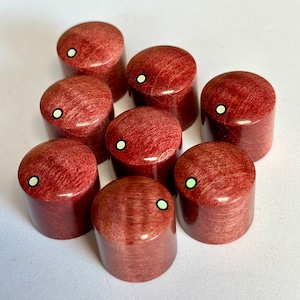 May include: Eight red wooden guitar knobs with white and green accents. The knobs have a unique wood grain pattern.