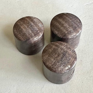 Puede incluir: Tres pomos de madera marrón con un patrón de veta de madera. Los pomos son redondos y tienen un acabado liso.