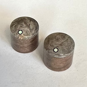 May include: Two wooden knobs with a marbled pattern in shades of brown and gray. Each knob has a white dot in the center.