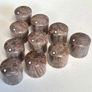 Puede incluir: Diez pomos de guitarra de madera con un patrón de veta de madera gris y marrón y un punto blanco en el centro de cada pomo.
