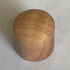 May include: A light brown wooden knob with a rounded top and a cylindrical base.
