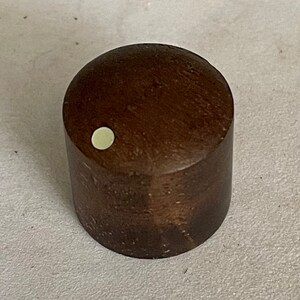 May include: A brown wooden knob with a white dot in the center.