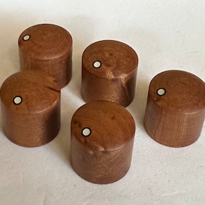 Könnte beinhalten: Fünf braune Holzknöpfe mit weißen Punkten in der Mitte. Die Knöpfe sind rund und haben eine glatte Oberfläche.