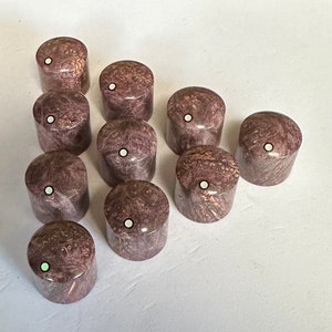 Puede incluir: Diez pomos de guitarra redondos, de mármol marrón y blanco con un punto blanco en el centro de cada pomo.
