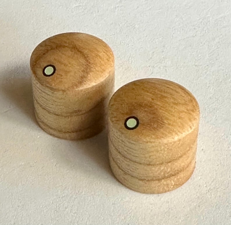 K&ouml;nnte beinhalten: Zwei Holzgriffe mit hellbrauner Oberfl&auml;che und einem wei&szlig;en Punkt in der Mitte. Die Griffe sind rund und haben eine leicht strukturierte Oberfl&auml;che.