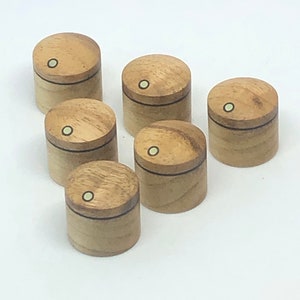 May include: Six wooden knobs with a black line around the top and a white dot in the center. The knobs are arranged in a semi-circle.