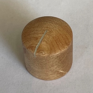 Puede incluir: Un pomo de madera de color marrón claro con una línea blanca que cruza la parte superior.