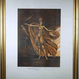 Op de afbeelding: Een ingelijste print van een vrouw in een vloeiende jurk, die een staf vasthoudt. De print is in tinten bruin en goud, en het gezicht van de vrouw is bedekt door een hoofdtooi. De print is gesigneerd en genummerd 246/300.